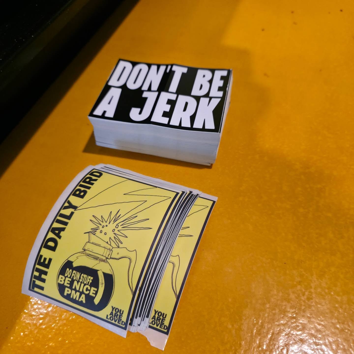 Daily Bird stickers and positive-message cards displayed on the shop counter